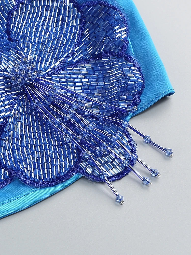 Close-up of a blue beaded flower accessory on a light gray background