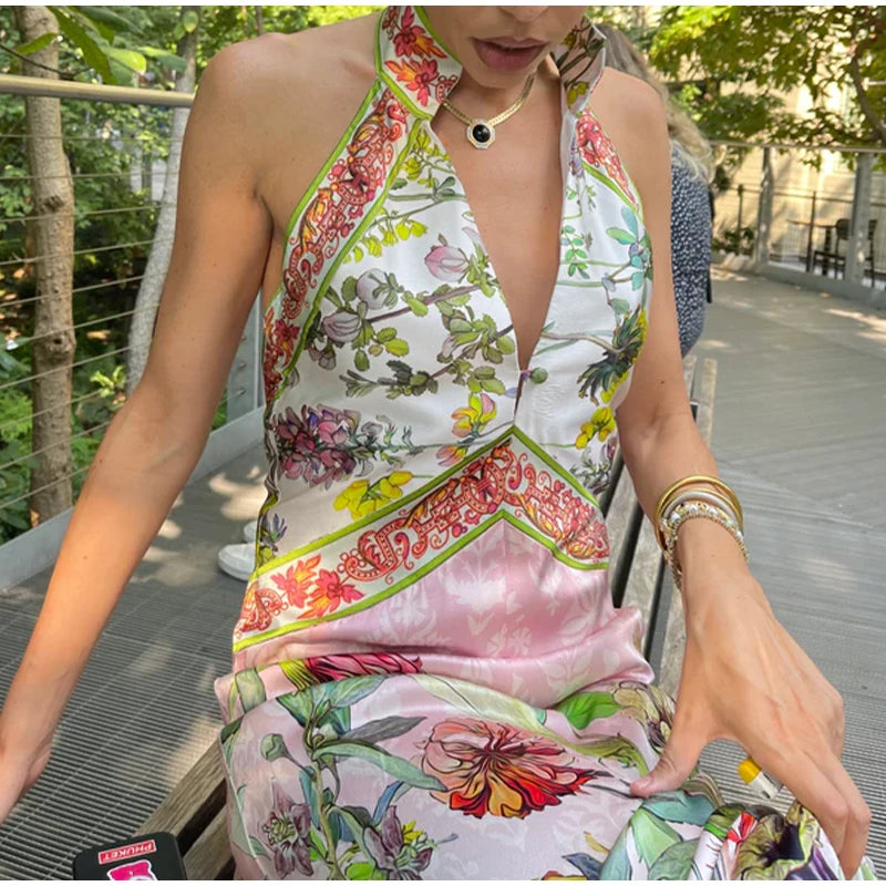 Woman wearing a colorful floral dress sitting outdoors.