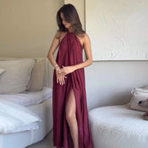 Woman wearing a burgundy halter neck dress with a slit in a modern living room.