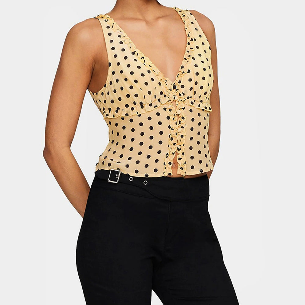 Woman wearing a yellow polka dot top and black pants on a white background