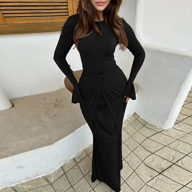 Woman wearing a black dress with a knot detail in an outdoor setting.