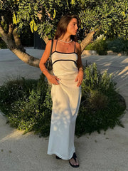 Woman in a white dress standing outdoors near greenery