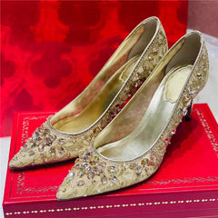 Gold high-heeled shoes with rhinestone embellishments on a red box.