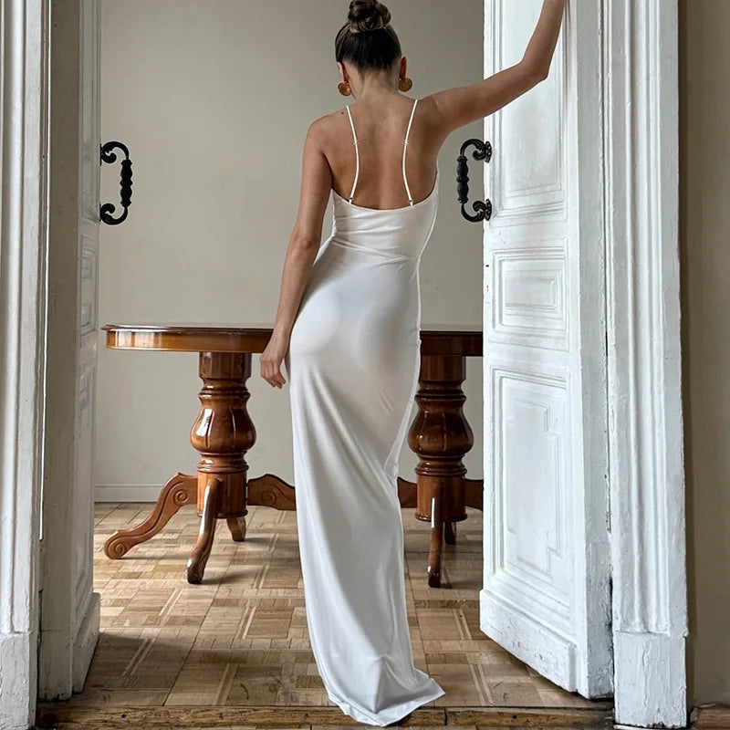 Woman in a white dress standing in a doorway with wooden furniture in the background