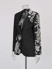 Black blazer with silver embroidery on a mannequin against a gray background
