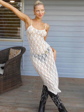 Woman wearing a white lace dress and black boots on a wooden deck.