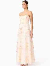 Woman wearing a strapless floral gown on a white background