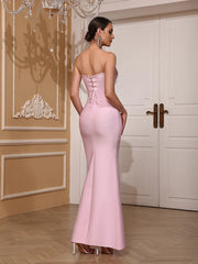 Woman in a pink evening gown standing in a room with decorative elements.