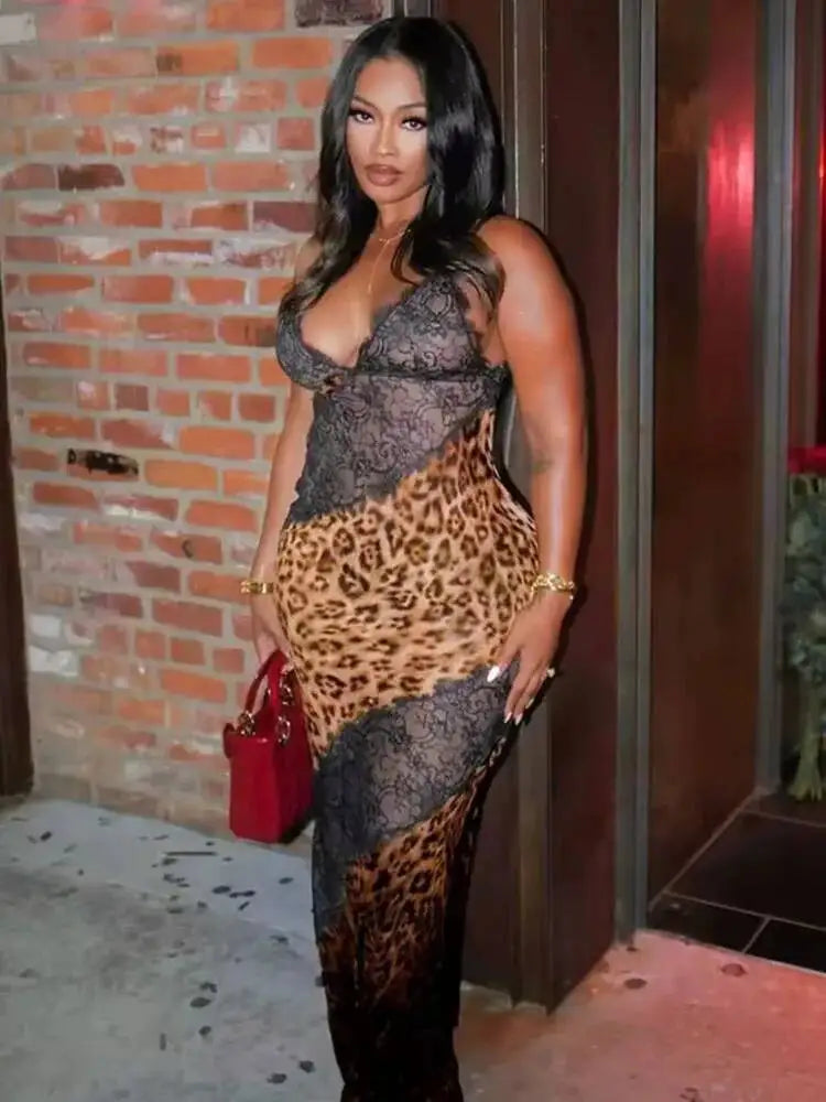 Woman wearing a leopard print dress with a red handbag against a brick wall.