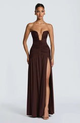 Woman wearing a strapless brown evening gown with a high slit on a white background