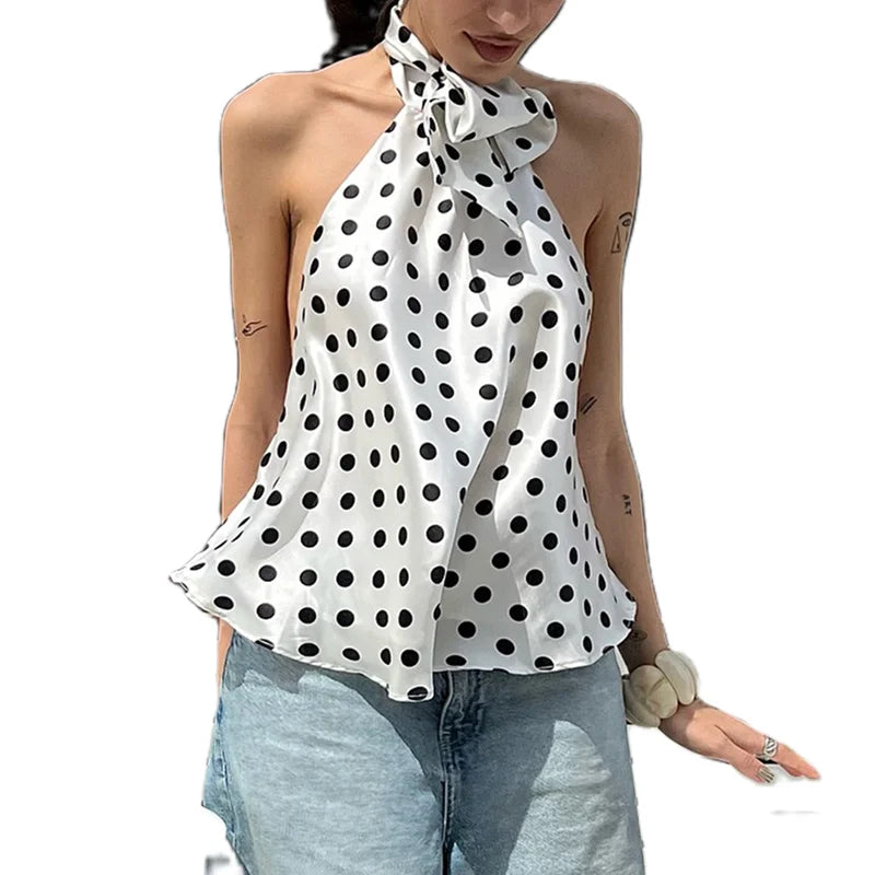 Woman wearing a white halter top with black polka dots and light blue jeans on a white background