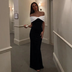 Woman in a black and white off-shoulder dress standing in a hallway.