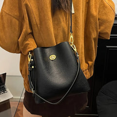 Person wearing a mustard yellow jacket with a black leather handbag featuring a gold clasp.