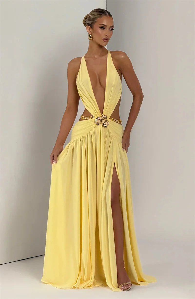 Woman wearing a yellow evening gown with a high slit on a plain background