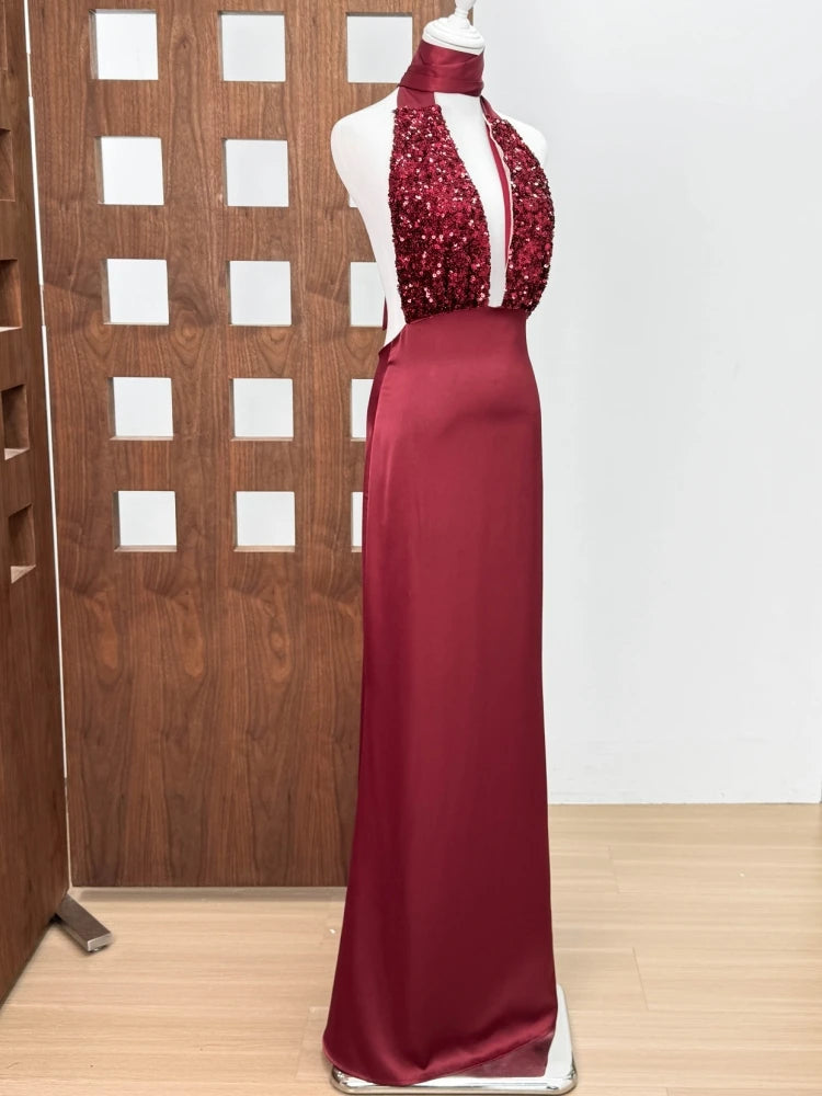 Red evening gown with sequined top on a mannequin against a wooden panel background