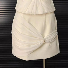 White dress with ruched design on a mannequin against a black background