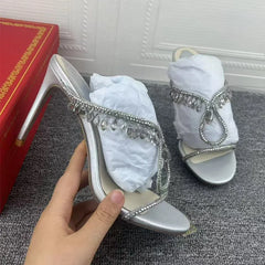 Silver high-heeled shoes with rhinestone details on a textured surface, with a red box in the background.