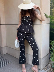 Woman in black polka dot strapless peplum top and flare pants with hat