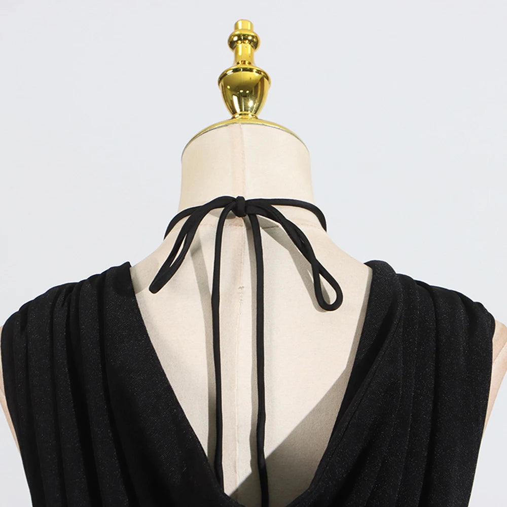 Black garment on a mannequin with a gold top against a light gray background