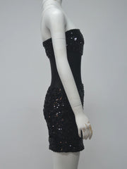 Black sequin dress on a mannequin against a gray background
