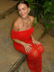 Woman in a red outfit sitting on stone steps with greenery in the background