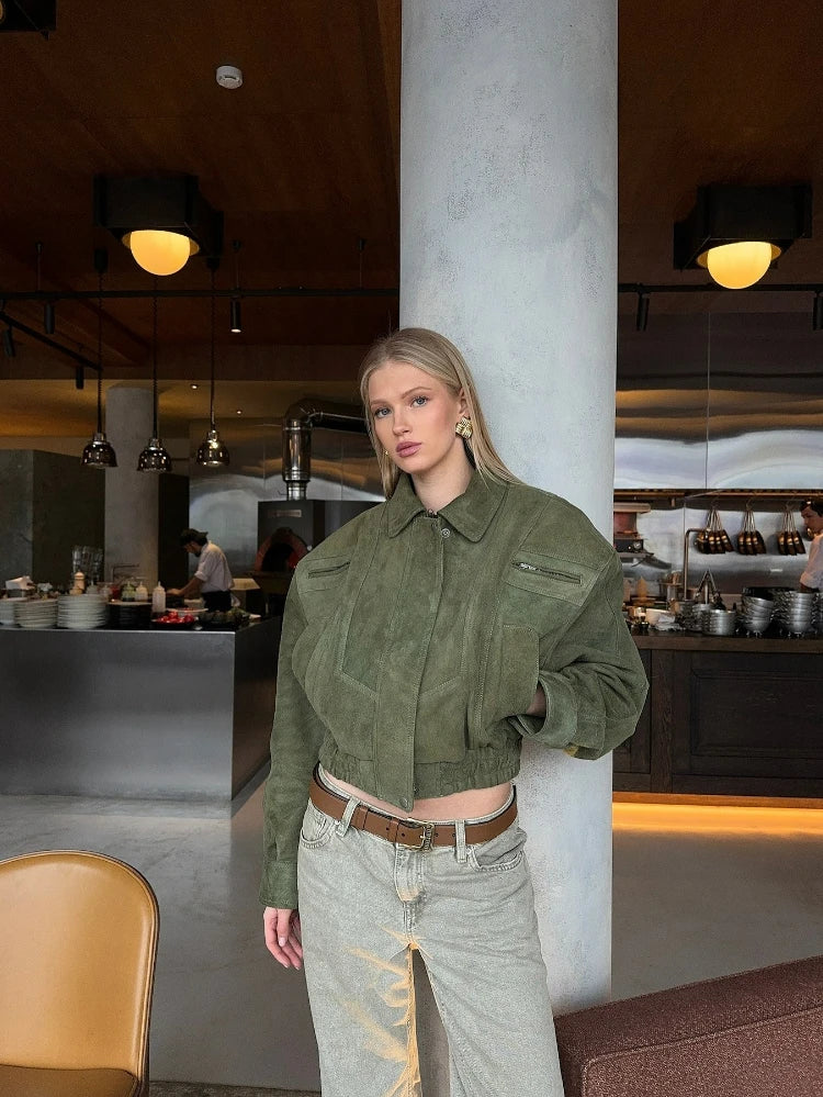 Woman in a green jacket standing in a modern interior setting