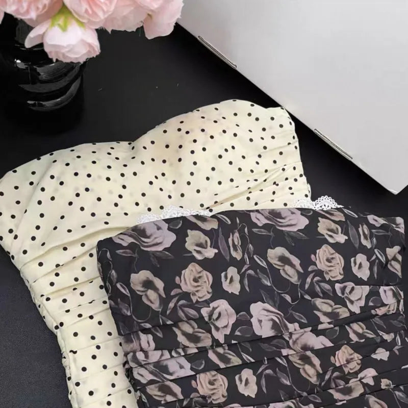 Two folded fabrics, one with black polka dots and the other with floral pattern, on a dark surface.