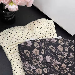 Two folded fabrics, one with black polka dots and the other with floral pattern, on a dark surface.