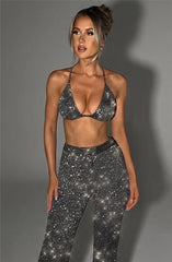 Woman wearing a sparkly silver top and leggings against a gray background