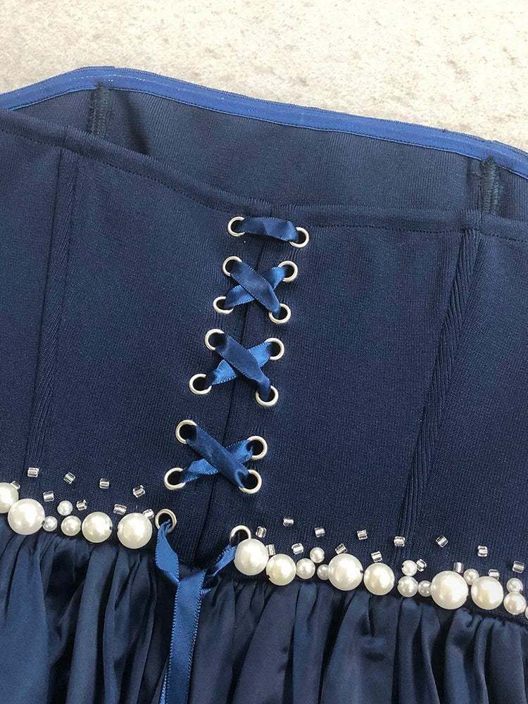 Navy blue corset with pearl embellishments on a textured surface