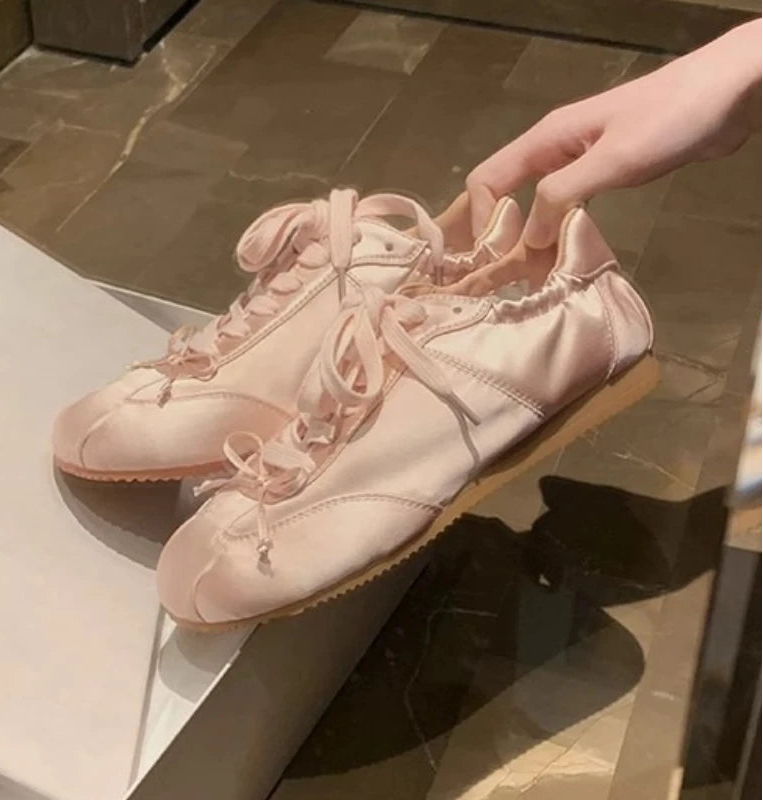 Close-up of pink satin ballet sneakers.