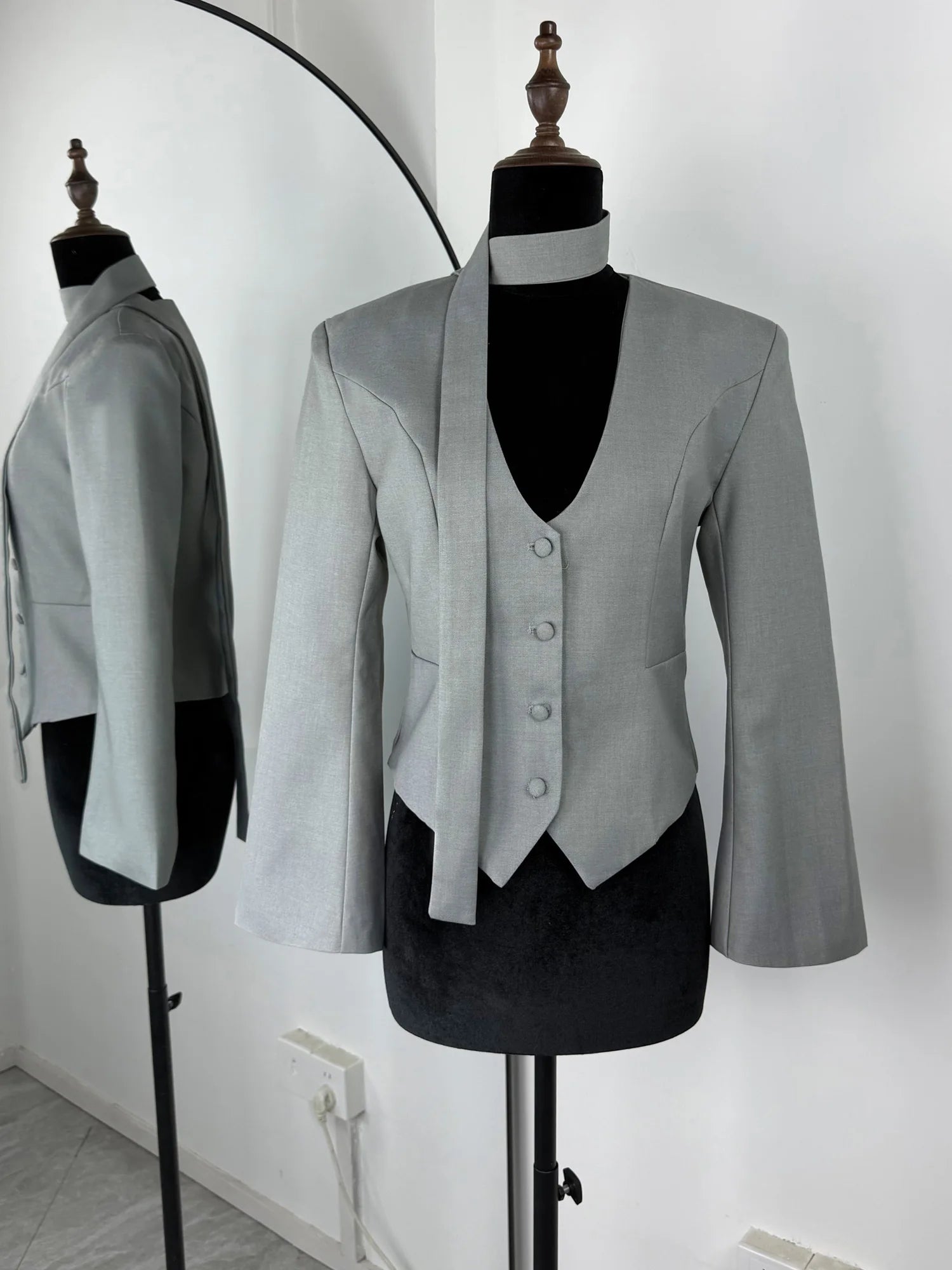 Gray blazer and vest set on mannequins against a white background