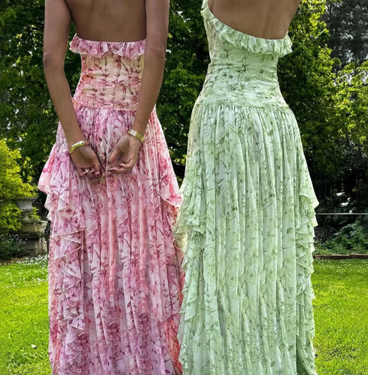 Two women wearing long, ruffled dresses in a garden setting.