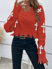 Red sweater with white cross patterns worn by a person against a light gray wall.