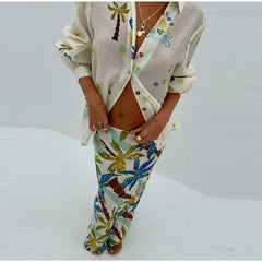 Person wearing a patterned shirt and colorful pants on a white background
