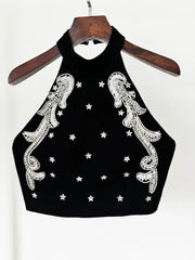 Black crop top with white embroidery and star patterns on a hanger against a white background