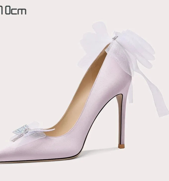 Pink high-heeled shoe with a bow and tulle on a white background