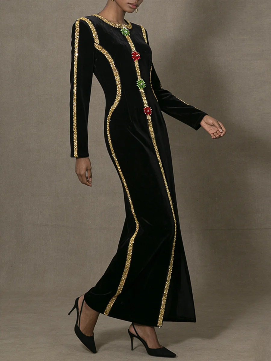 Black dress with gold trim and colorful stones on a neutral background