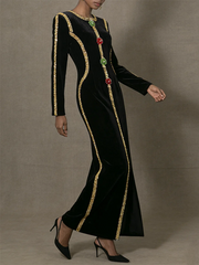 Black dress with gold trim and colorful stones on a neutral background