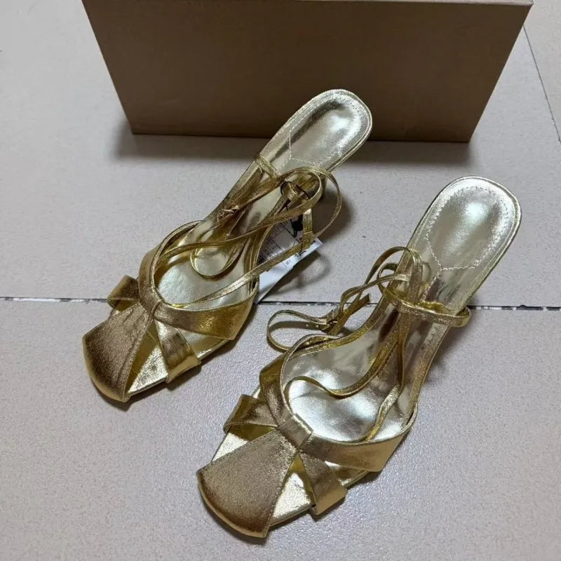 Gold satin stiletto heels with bow detail and ankle straps