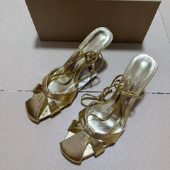 Gold satin stiletto heels with bow detail and ankle straps