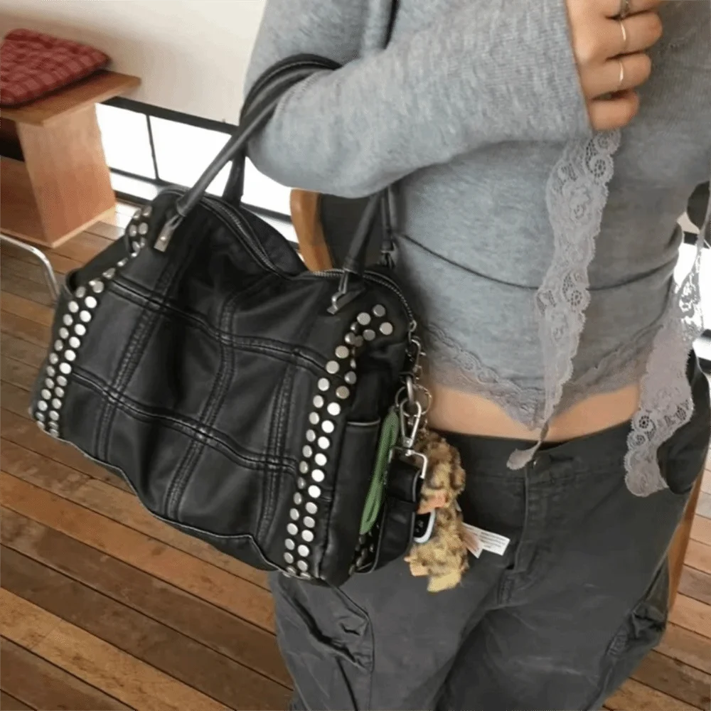 Person carrying a black quilted rivet tote bag