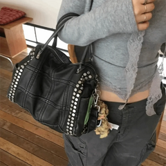 Person carrying a black quilted rivet tote bag