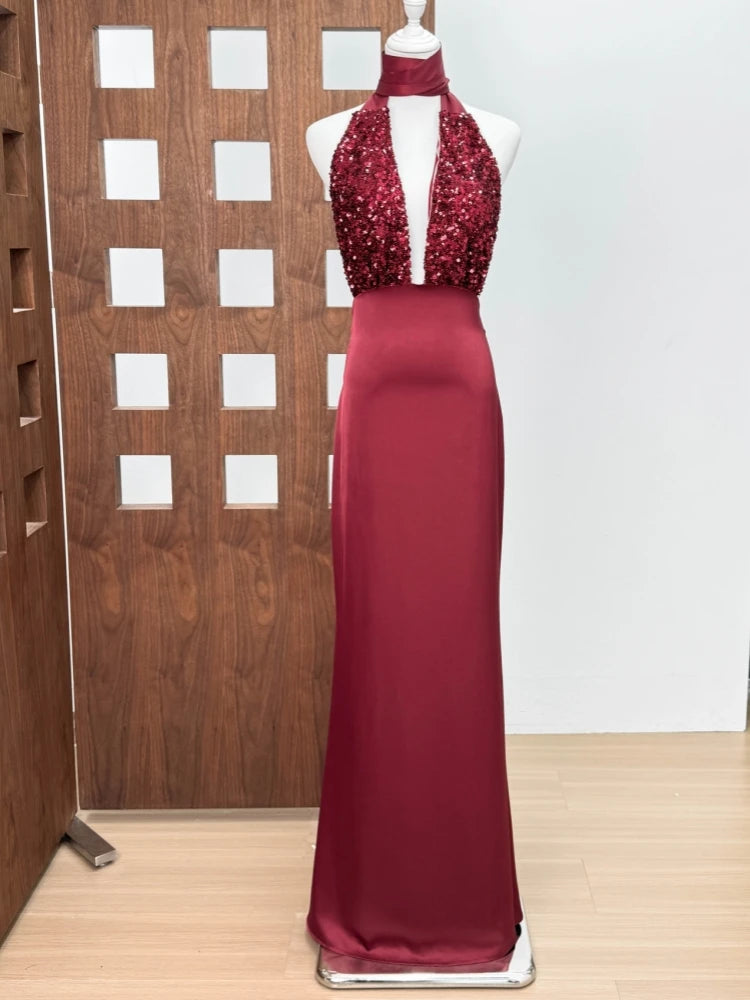 Red evening gown with sequined top on a mannequin against a wooden panel background