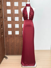 Red evening gown with sequined top on a mannequin against a wooden panel background