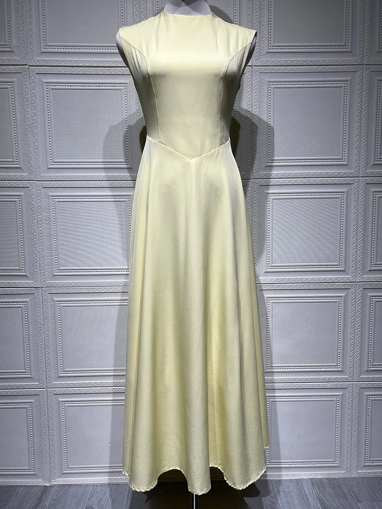 Light yellow dress on a mannequin against a gray paneled wall.
