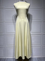 Light yellow dress on a mannequin against a gray paneled wall.