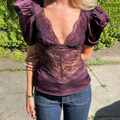 Person wearing a purple lace top and jeans outdoors.