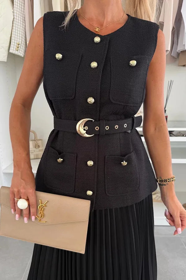 Woman wearing a black sleeveless jacket with gold buttons and a beige clutch.