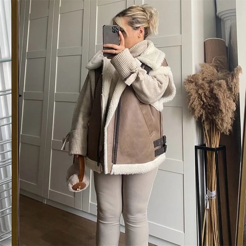 Person wearing a beige and brown jacket with fur lining, taking a mirror selfie.